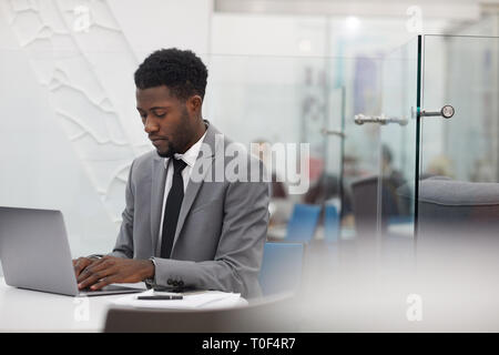 Portrait von stattlichen Afro-amerikanische Geschäftsmann mit Laptop, während im Büro arbeiten, kopieren Raum Stockfoto