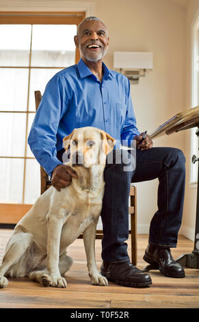 Lächelnd Mann sitzt und klapse Hund Stockfoto