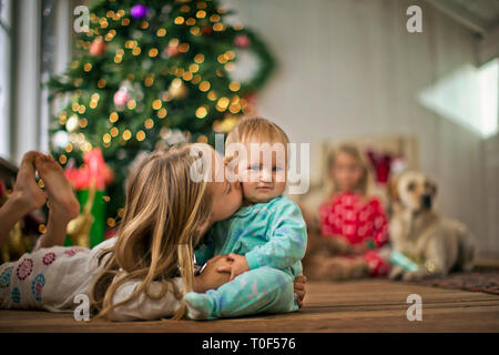 Junge Mädchen küsste ihre kleine Schwester auf die Wange. Stockfoto