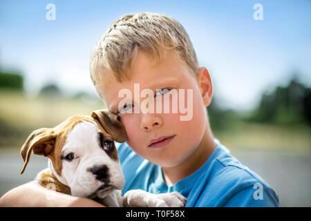 Porträt eines Jungen seine Bulldogge Welpen halten. Stockfoto