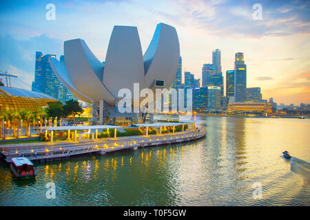 Singapur - Januar 3, 2017: Sonnenuntergang über beleuchtete Marina Bay Skyline mit ArtScience Museum lotus Gebäude der modernen Architektur im Vordergrund, Si Stockfoto