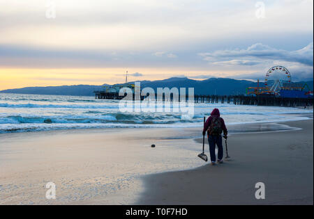 Prospector mit Metalldetektor auf der suche nach vergrabenen Schatz in Santa Monica Beach Stockfoto