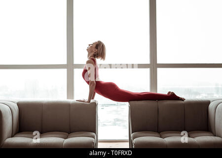 Ansprechende starke Frau im hellen roten Outfit durchführen Yoga Stockfoto