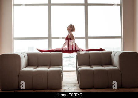 Elastische dünne Mädchen Yoga auf den Möbeln im Wohnzimmer Stockfoto