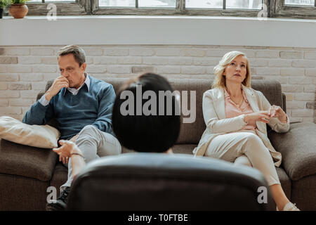 Verwirrt und verärgert nach paar sitzen auf unterschiedlichen Seiten des Tisches Stockfoto