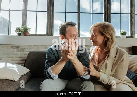 Gut aussehendes Paar mittleren Alters sich einander während der Sitzung Stockfoto