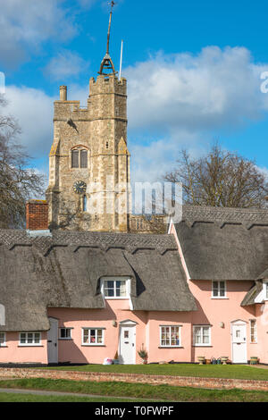 Reetdachhaus in Suffolk rosa mit St. Maria der Jungfrau Kirche auf dem Dorf grün lackiert. Cavendish, Suffolk, East Anglia, Großbritannien. Stockfoto