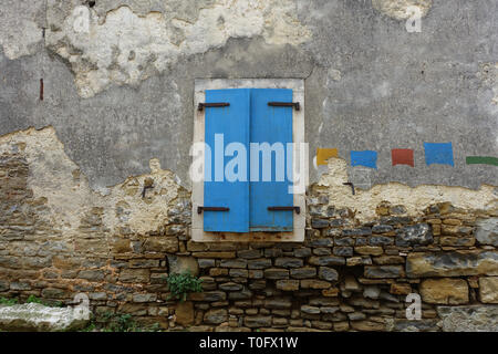 Farbenfrohe blaue Fenster, die gegen eine alte Mauer aus Stein, die in einer kleinen Stadt in Kroatien Stockfoto