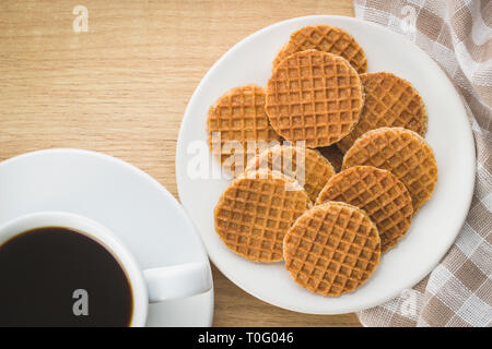 Süße Waffel Kekse auf dem Teller und Tasse Kaffee am Küchentisch. Stockfoto