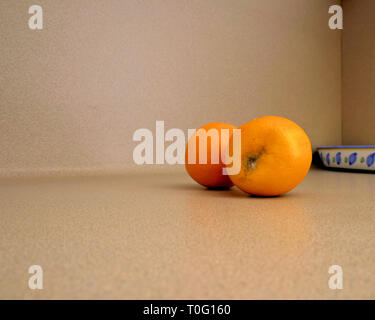 Zwei Orangen auf eine Küche Zähler nach oben; eine verwesende Orange; eine reife Orange; Konzept für die Laufe der Zeit oder Alter Unterschied. Stockfoto