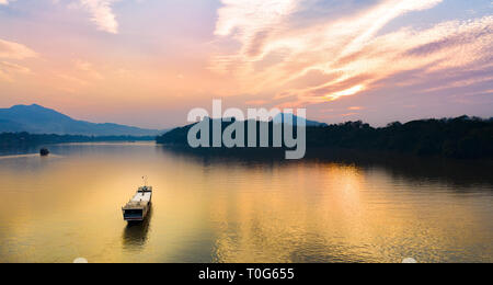 Ansicht von oben, beeindruckende Luftaufnahme eines Touristen Boot segeln entlang des Mekong bei Sonnenuntergang. Stockfoto