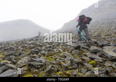 Zwei Wanderer klettern die steinigen steilen Hügel, Wolken über die Berge, Fallen in Spitzbergen, Svalbard, Norwegen hängen Stockfoto