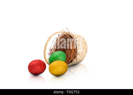 Bunte Ostereier aus Nest auf Holz- korb über weißem Hintergrund verschüttet. Frohe Ostern Stockfoto