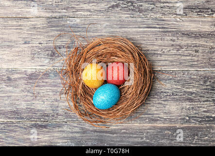 Bunte Ostereier im Nest auf Holztisch. Frohe Ostern Stockfoto