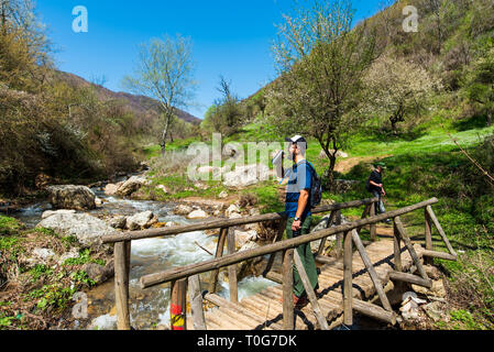 Man Trinkwasser die hölzerne Brücke über den kleinen Fluss im Freien Stockfoto