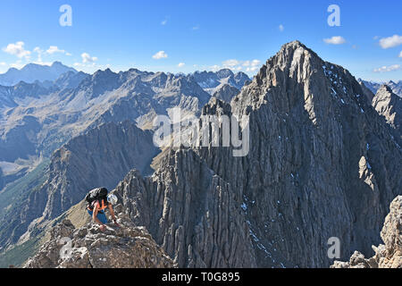 Frau klettern in eine wilde felsige Landschaft mit steilen Bergen unter blauem Himmel an einem schönen Tag. Dremelspitze, Lechtaler Alpen, Tirol, Österreich. Stockfoto