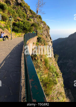 Touristen auf einer Bank am Aussichtspunkt und bewundern Sie die dramatische Bergblick am späten Nachmittag Sonnenlicht, Miradouro Da Eira Do Serrado, Madeira/Port Stockfoto