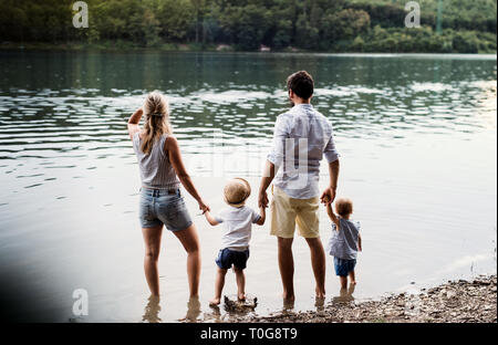 Ein junge Familie mit 2 Kleinkind Kinder die Zeit draußen am Fluss im Sommer. Stockfoto