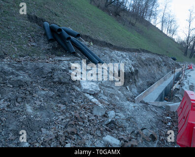 Zur Reparatur Wasserleitung im Boden. Konstruktion auf einem Hügel mit graben Graben und schwarz Wellrohr Stockfoto
