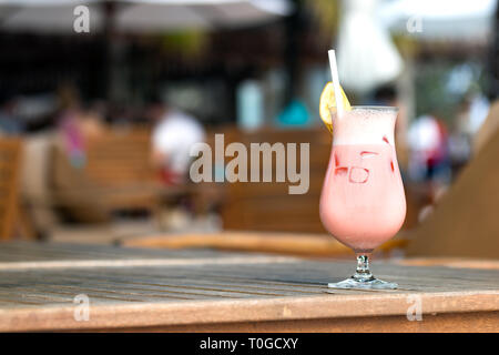 Cocktail mit Früchten, einer Scheibe Banane auf der Oberseite und Stroh auf einen hölzernen Tisch in Malediven. Stockfoto