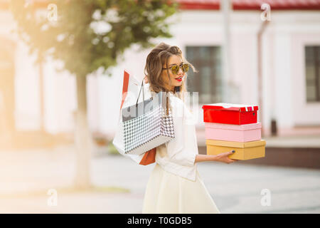 Gerne Modell in Weiß sieht und Sonnenbrille holding Einkaufstaschen u Stockfoto