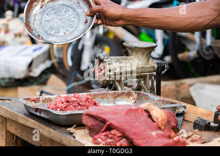 Hand weg fliegt über Hackfleisch neben einem Schleifer im Freien in Toliara, Madagaskar. Stockfoto