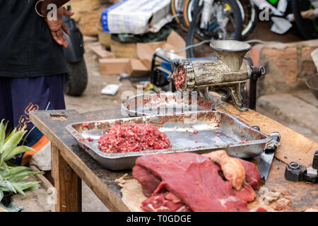 Rohes Hackfleisch und ein Schleifer mit Fliegen im Freien in Toliara, Madagaskar. Stockfoto