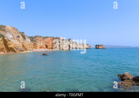 Einen einsamen Sandstrand von Klippen in kleinen Hafen entlang der Küste der Algarve, Portugal umgeben. Schöne Landschaft mit natürlichen Grotten und Reef Stockfoto