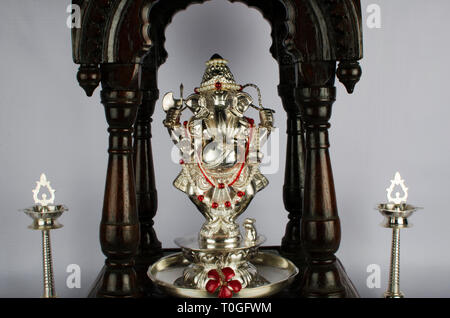 Silver Lord Ganesh Idol in einer traditionellen antiken Holz Maharashtrian devara oder Puja Zimmer oder Kapelle und zwei traditionelle indische Samai oder Lampen k platziert Stockfoto