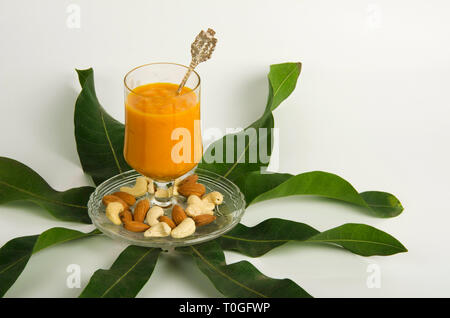 Glas Mango Pulp gehalten in einer Petrischale mit Cashew und Mandeln am 8 Mango Blätter angezeigt. Stockfoto