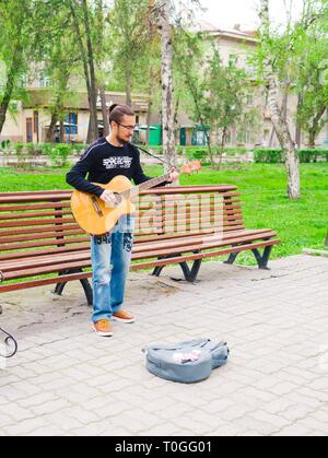 Bischkek, Kirgisistan - April 14, 2018: Ein schöner Mann führt mit einer Gitarre beim Karneval neben der Bank. Stockfoto