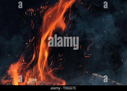 Ein Schuß von brennendem Holz in den Kamin. Close-up. Das Verbrennen von Holz zum Grillen ein. Rauch und Funken. Feuer Hintergrund. Stockfoto