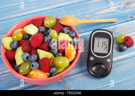 Salat von frischen Früchten und Blutzucker-messgerät mit Ergebnis der Messung Blutzucker, Diabetes, Abnehmen, gesunde Lebensführung und Ernährung Stockfoto