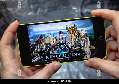 Berdyansk, Ukraine - 16. März 2019: Hände, die ein Smartphone mit Lineage 2 revolution Spiel auf dem Anzeigebildschirm angezeigt. Stockfoto