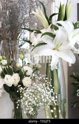 Viele Glas Vasen werden von Lilien, Lisianthus und Gypsophila für eingerichtetes Wohnzimmer enthalten Stockfoto