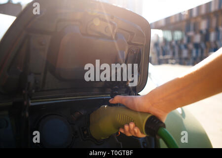 Elektrofahrzeug Ladestation. Männliche hand Aufladen eines Elektroautos mit dem Netzkabel Netzteil angeschlossen. Eco-friendly Car für Umwelt Stockfoto