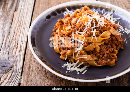 Fettuccine Pasta mit Sauce Bolognese und Thymian, köstliche italienische Gerichte serviert mit geriebenem Parmesan auf rustikalen Holztisch Stockfoto