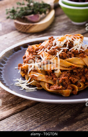 Fettuccine Pasta mit Sauce Bolognese und Thymian, köstliche italienische Gerichte serviert mit geriebenem Parmesan auf rustikalen Holztisch Stockfoto