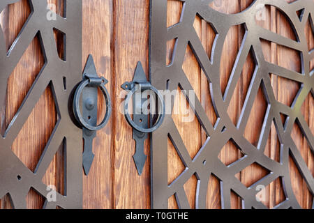 Holztor mit geschmiedetem Metall Elementen. runde Metall Griff schließen. Hintergrund Textur. Stockfoto