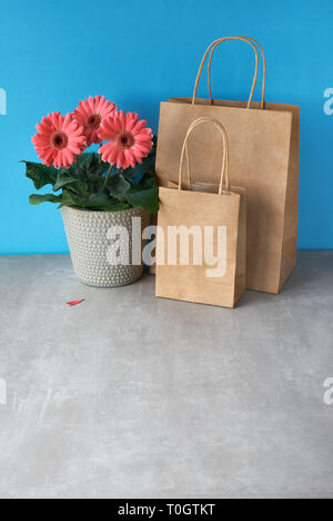 Coral Gerbera daisy flowers und Handwerk papper Einkaufstaschen. Frühling Verkauf Konzept Bild mit copy-Raum Stockfoto