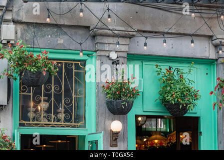 Die Altstadt von Montreal, Quebec, Kanada. Hängenden Blumenkörben über ein konkretes Gebäude Eingang mit Jade Grün Holz Türen und Fenster, Saint Paul St. West. Stockfoto