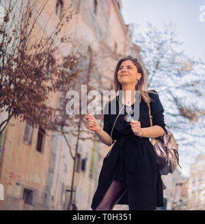Jung, schön und modische Frau Wandern auf den Jahrgang Straße mit Kopfhörern und genießen die Musik Stockfoto