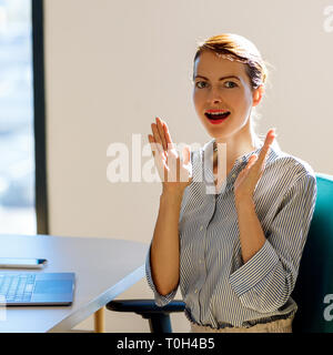 Überrascht business Frau am Schreibtisch im Büro zu sitzen. Stockfoto