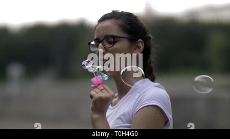 Mädchen in Gläsern bläst Seifenblasen slow motion, Spaß haben Stockfoto