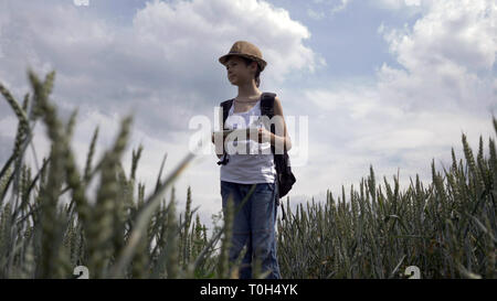 Glückliche junge Reisende bei Map auf Tablet stehen im Feld, im Freien suchen, haben Spaß Stockfoto