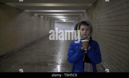 Junge Spaziergänge durch den Tunnel im Winter und trinkt Kaffee Stockfoto