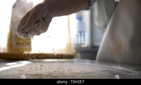 Weibliche hand verschütten Mehl auf den Tisch Stockfoto