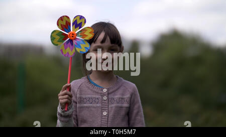 Schöne Mädchen mit Mühle Spielzeug auf dem Natur lächelnd und mit Blick auf die Kamera Stockfoto