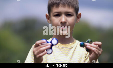 Happy Boy Holding spielen zwei zappeln Spinner auf die Natur Stockfoto