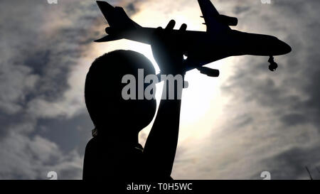Silhouette Junge spielt mit Spielzeug Flugzeug gegen schönen Himmel, haben Spaß Stockfoto